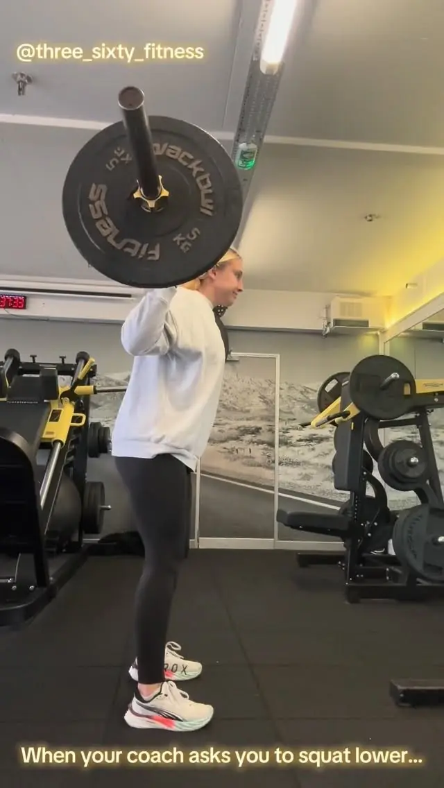 A member squatting with a loaded barbell in the gym