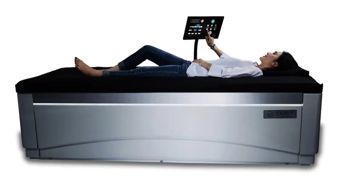 A woman lying fully clothed on a TheraJet massage bed